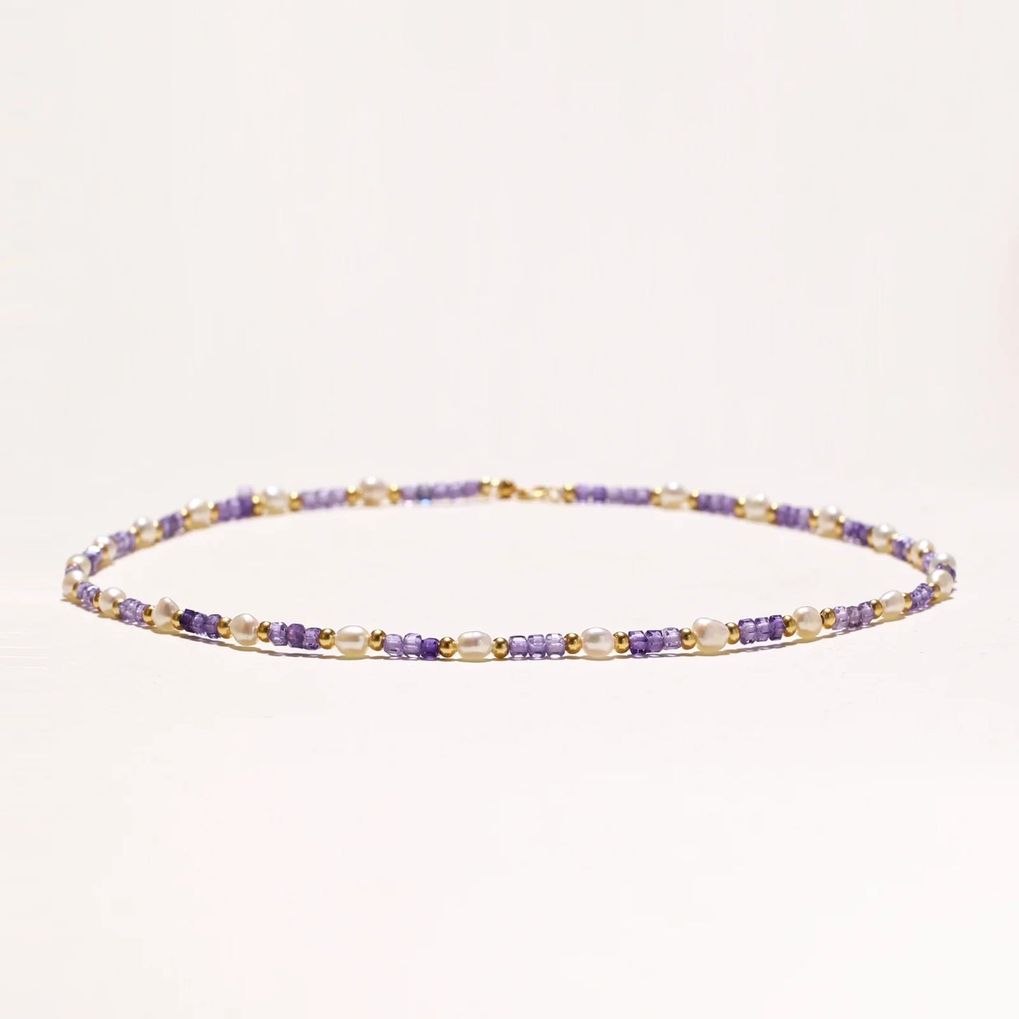 Delicate 18K gold vermeil necklace with alternating lavender zirconia beads and white freshwater pearls on cream background