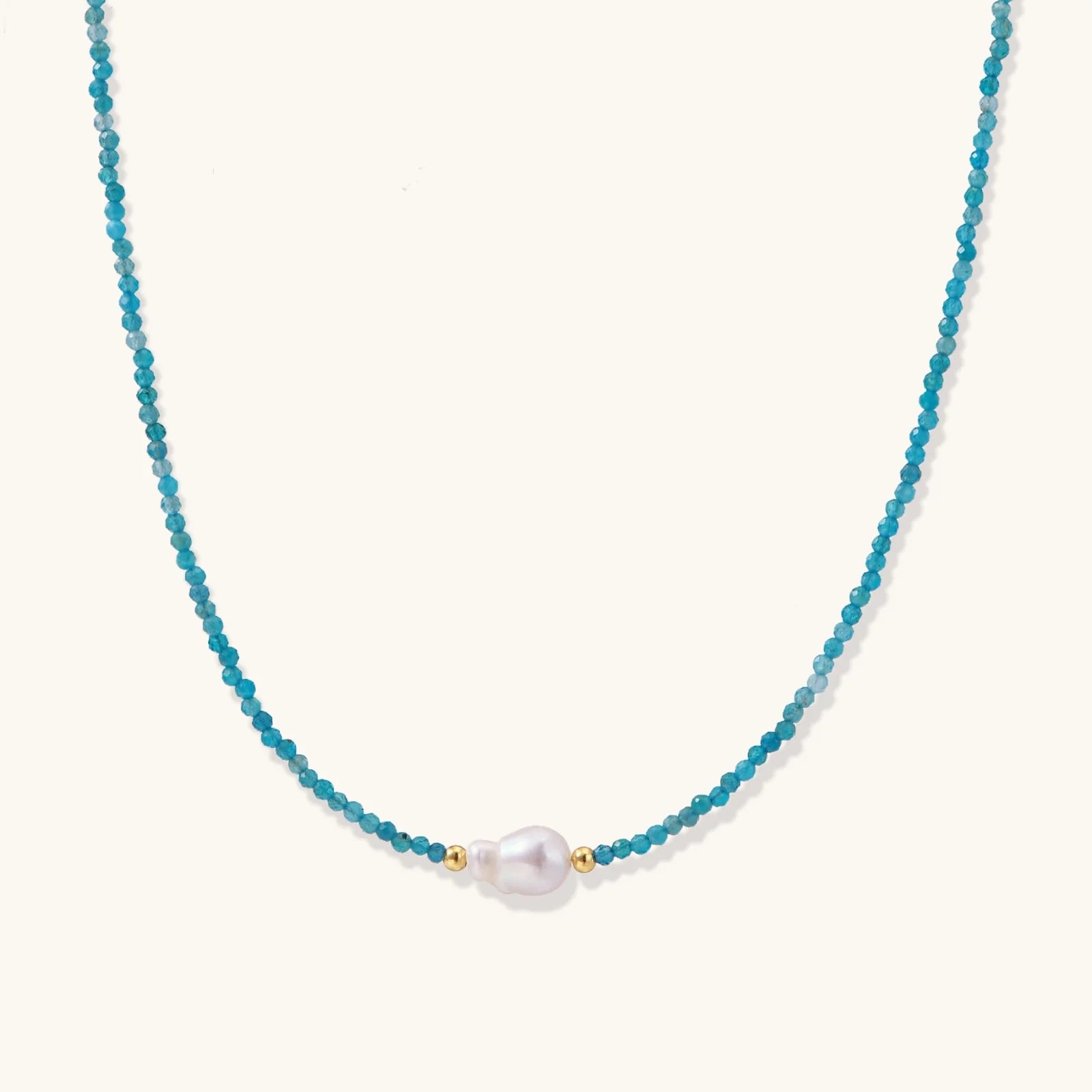 Delicate gold vermeil necklace with teal apatite beads and freshwater pearl on white background.