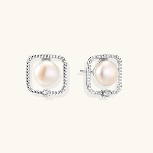 Rhodium-plated silver stud earrings with cushion frame, centered freshwater pearl, and tiny crystal accent