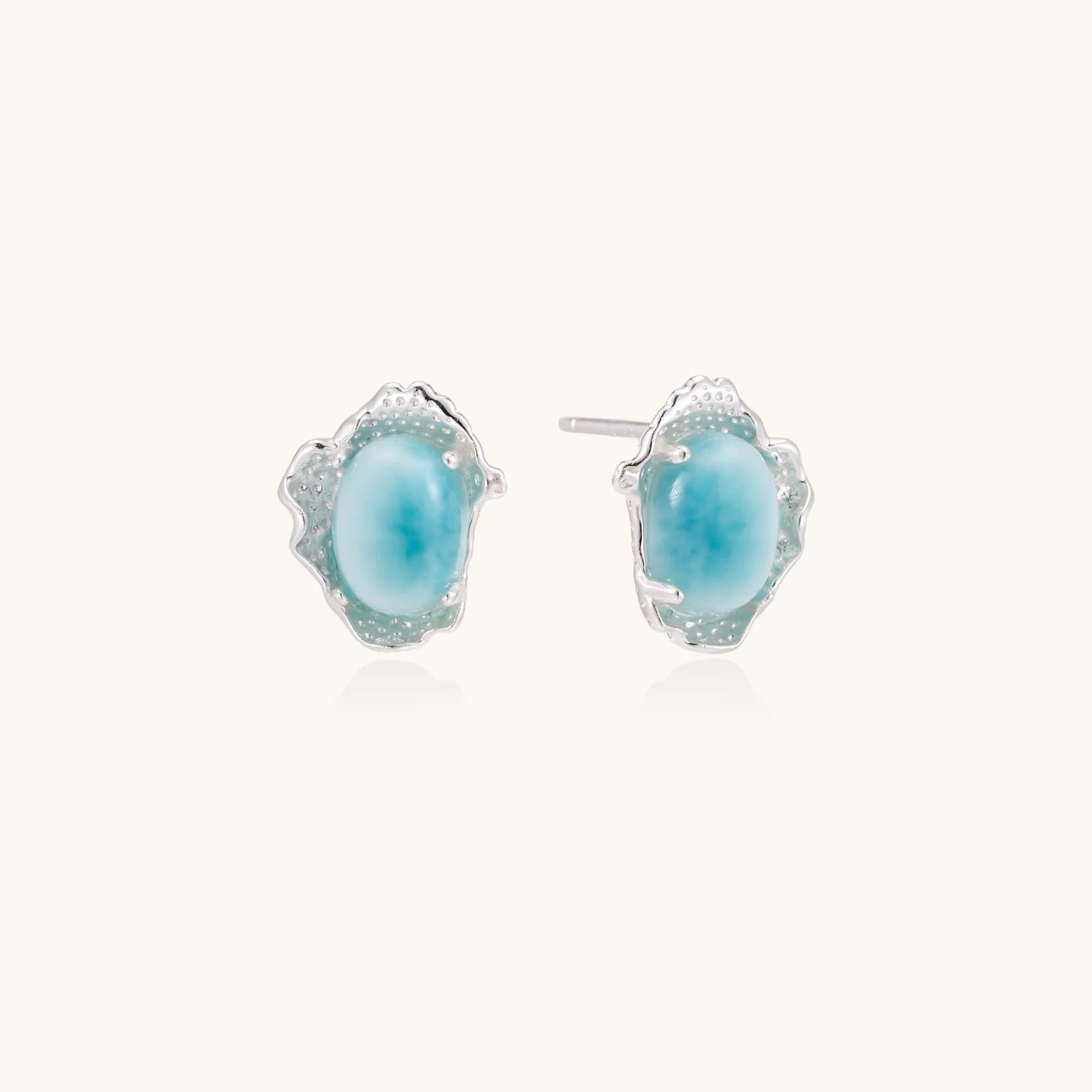 Oval larimar gemstone studs with ornate silver settings showing natural turquoise marbling on cream background