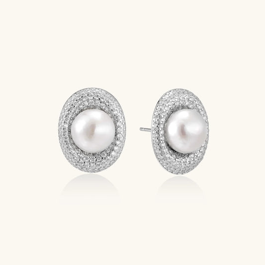 Oval rhodium-plated silver studs featuring freshwater pearls surrounded by pavé crystal halo on white background