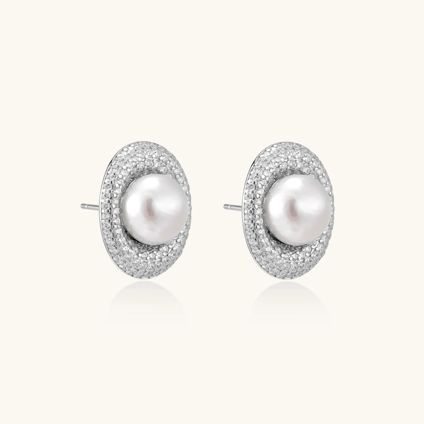 Oval rhodium-plated silver studs featuring freshwater pearls surrounded by pavé crystal halo on white background