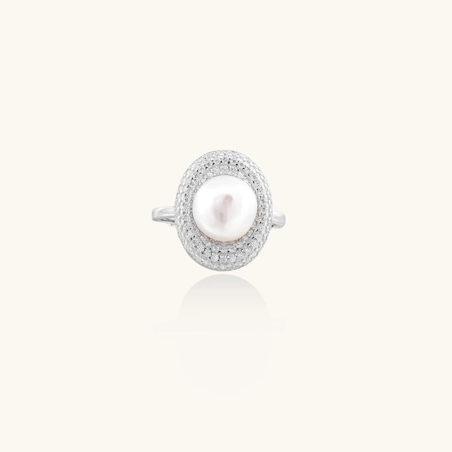 Silver ring with lustrous white pearl center surrounded by sparkling crystal halo on light background.