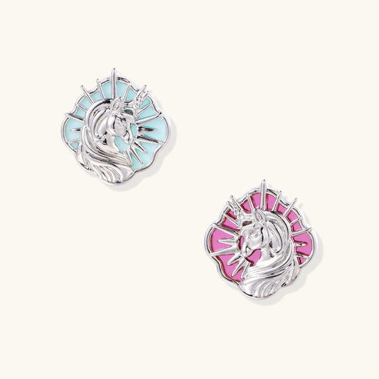 Silver unicorn stud earrings with pastel blue and pink enamel stones in sunburst prong settings on cream background
