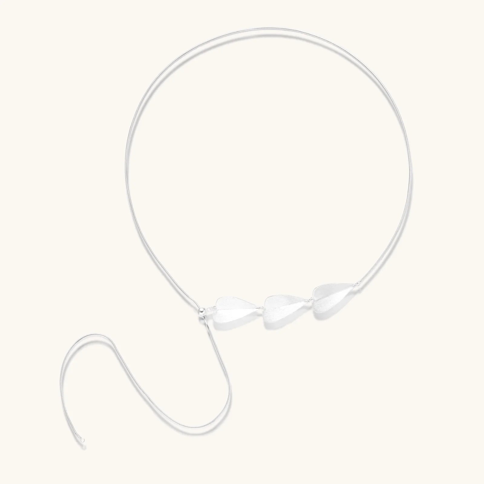 Minimalist sterling silver necklace with three brushed leaf-shaped pendants on delicate chain against white background