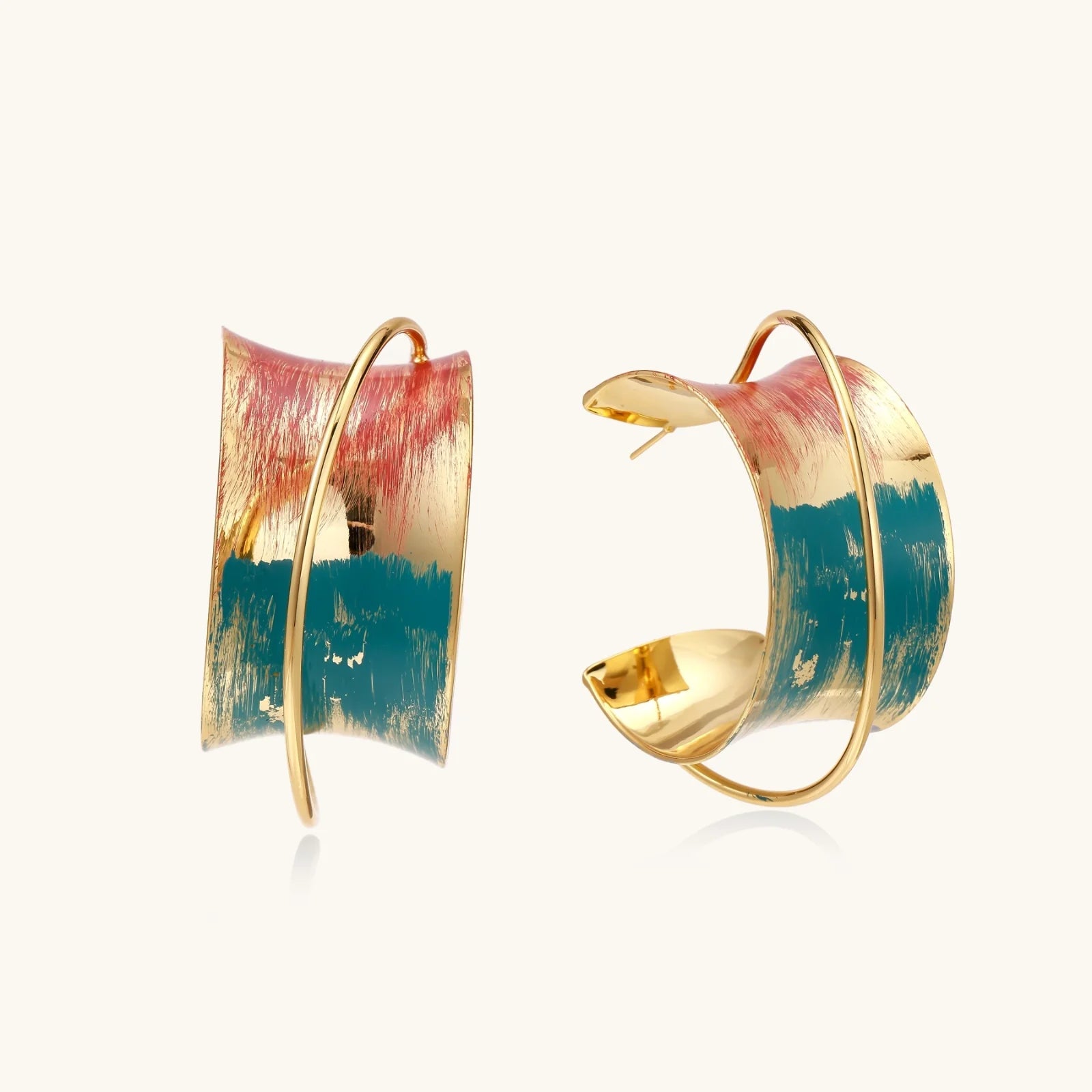 Gold-plated hoop earrings with teal and coral enamel brushstroke design on cream background