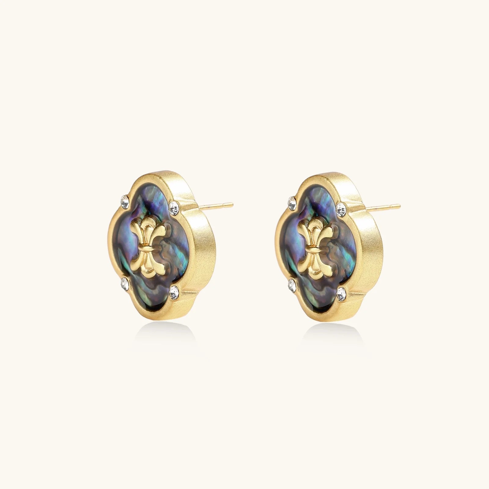 Gold quatrefoil stud earrings with iridescent abalone shell inlay and fleur-de-lis center, accented by four crystals