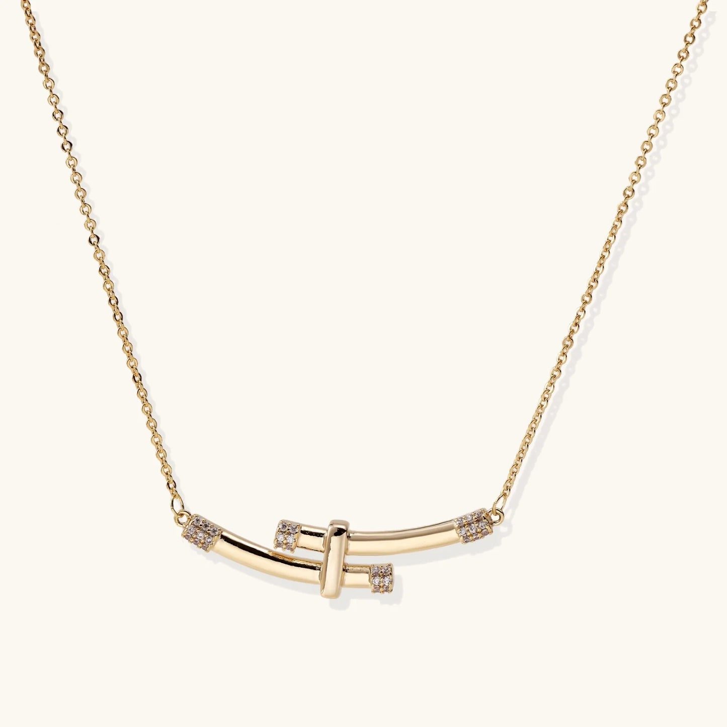 Gold-plated curved bar necklace with diamond accents on delicate chain against cream background