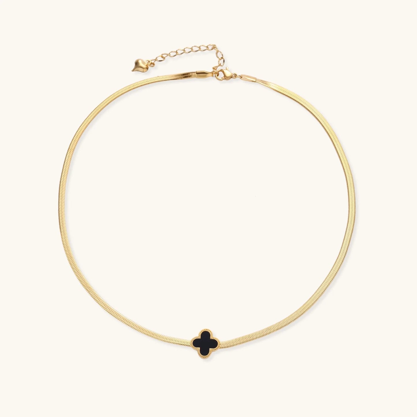 Dainty 18K gold-plated herringbone chain necklace with black enamel quatrefoil clover pendant on white background